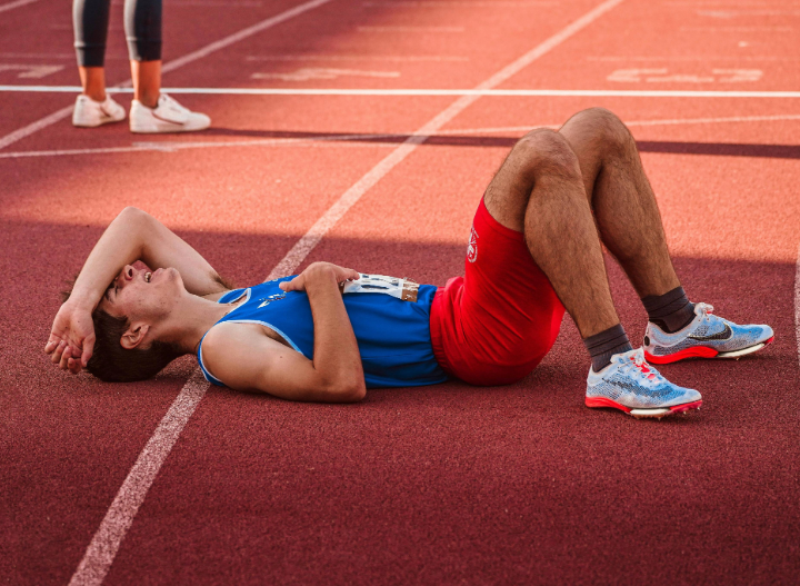 an athlete laying down on a track appearing exhausting after running a race