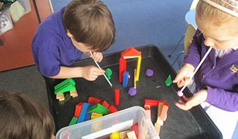 Kids using straws to blow over building blocks