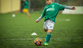 A child in football kit kicking a ball