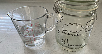 A water jug half filled and a mason jar with illustrations of the water cycle