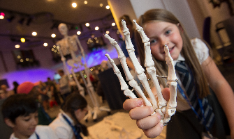 child attending PSTT's international conference holding up a skeleton hand for the camera