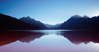 an image of mountains and the sky reflecting beside a body of water
