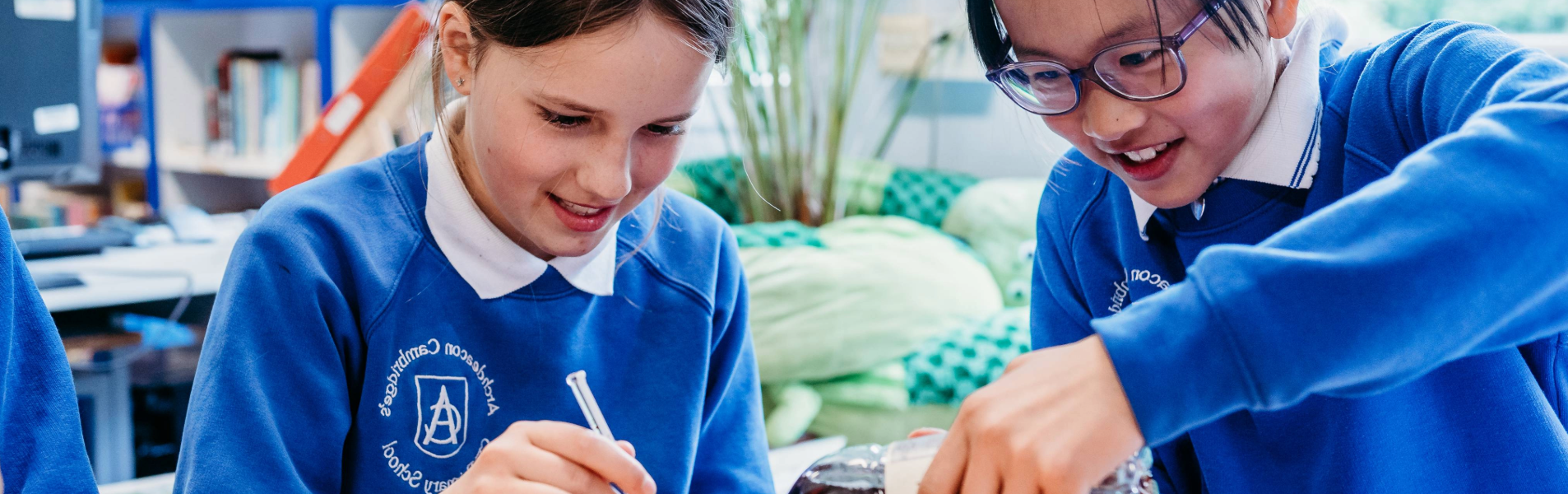 Two primary school children working together on a hands-on science activity in a classroom