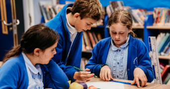 Three primary school pupils working together on a science activity in a classroom