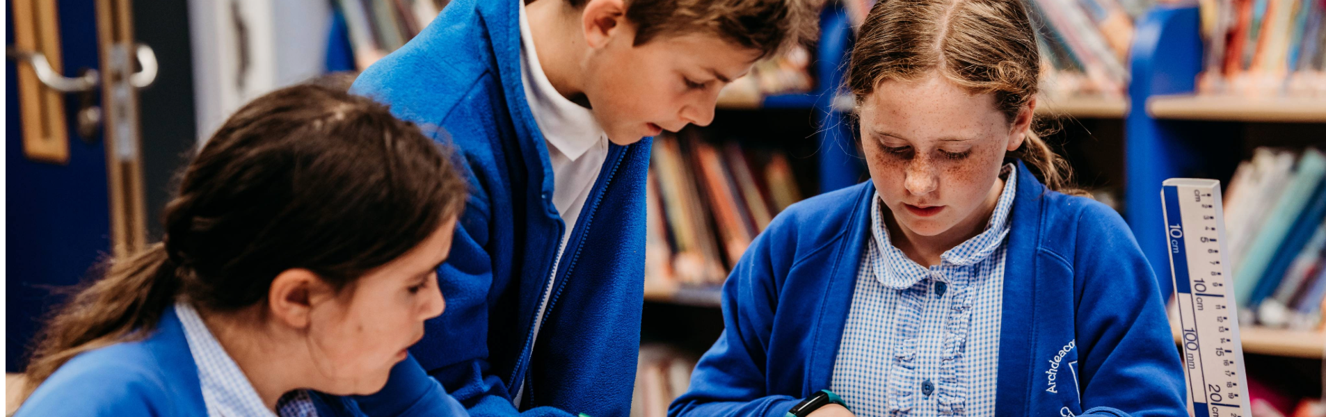 Three primary school pupils working together on a science activity in a classroom