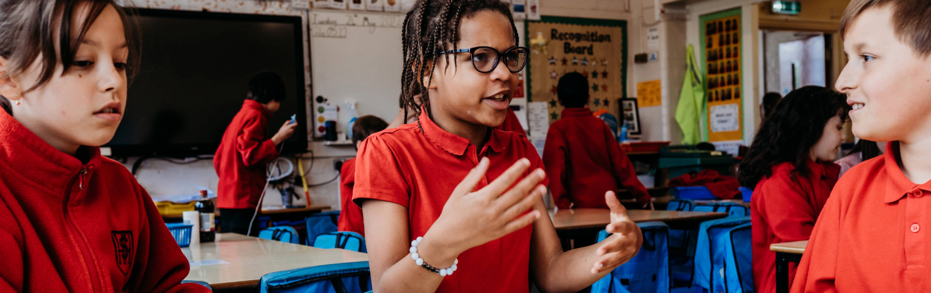 primary school children in a classroom discussing ideas in small groups during a science activity