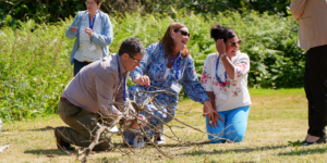 Teachers taking part in an outdoor practical science activity, examining branches and natural materials together during a professional learning event